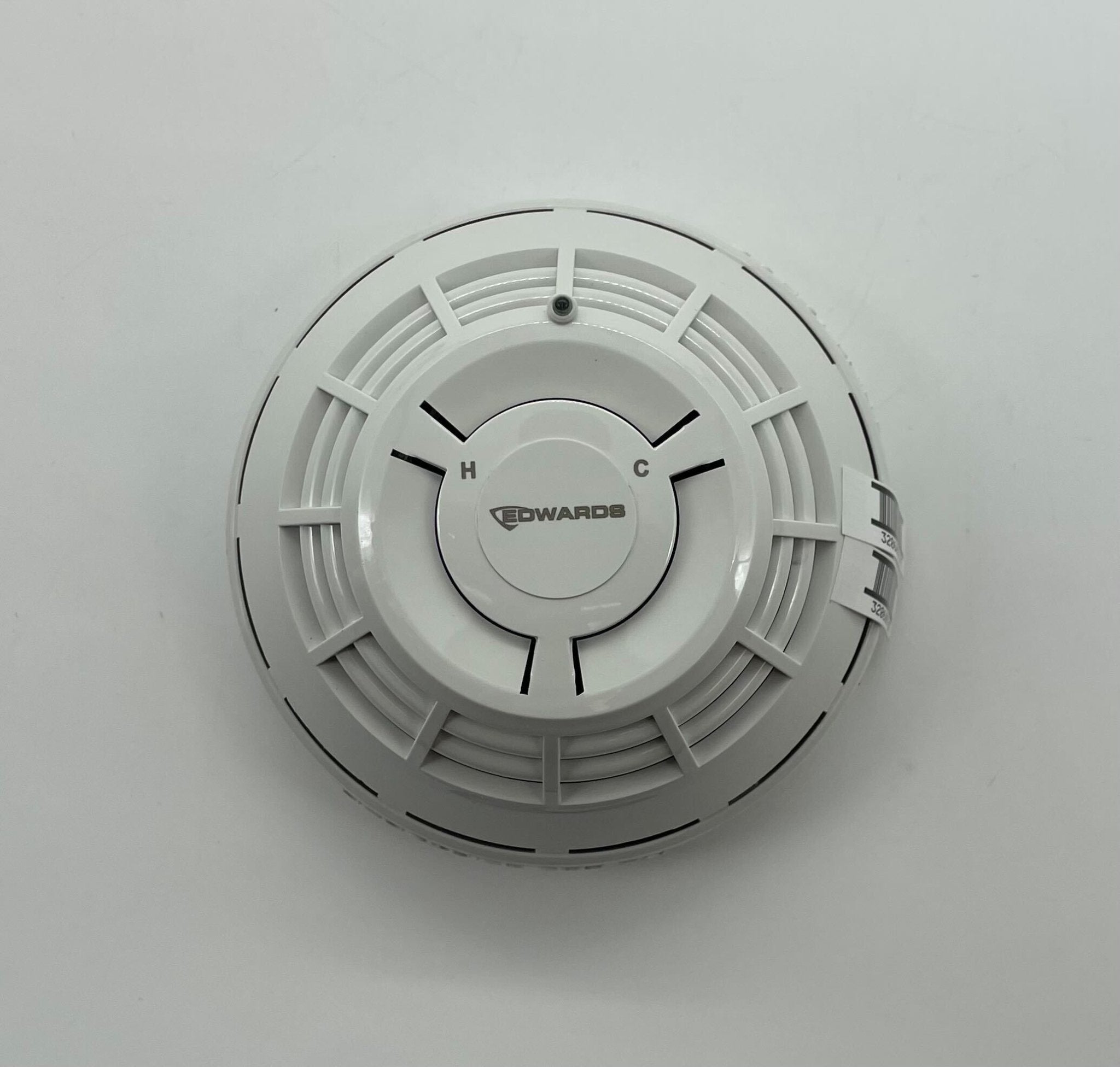 Edwards SIGA-HCD heat detector mounted on wall, part of Edwards fire safety system, with white plastic housing and mounting bracket.