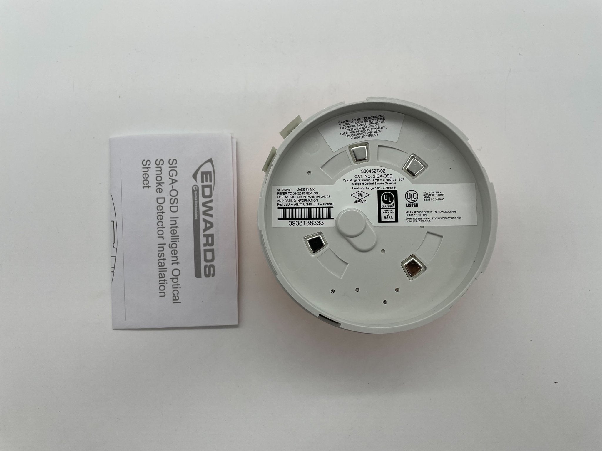 Edwards SIGA-OSD smoke detector mounted on ceiling, black and white sensor device by Edwards for fire safety.