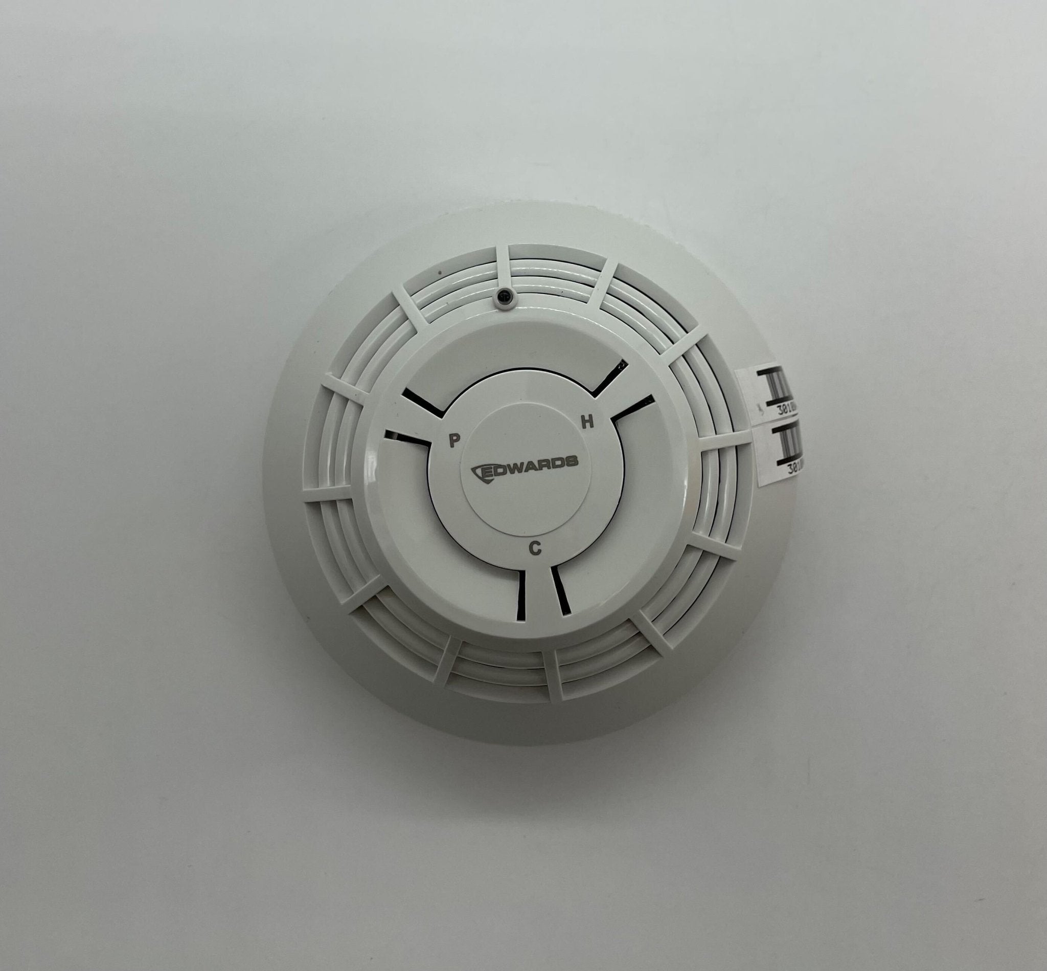 Edwards SIGA-PHCD heat detector with white casing, mounted on a ceiling, designed for fire safety in commercial buildings.