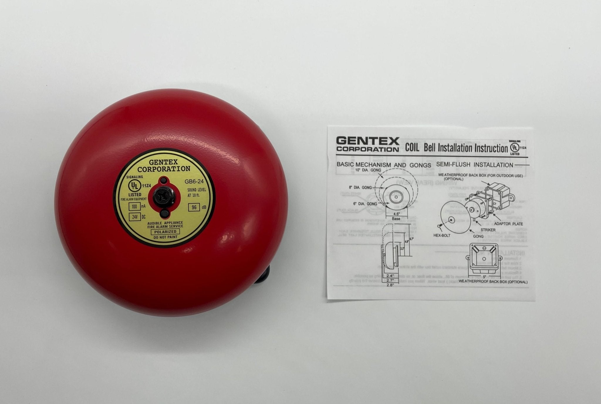 Gentex GB6-24 6-inch fire alarm bell mounted on a wall, with metal housing and mounting bracket.