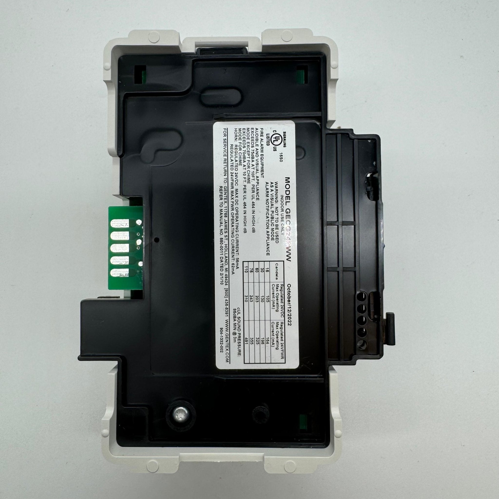 Gentex GECG24PWW fire alarm horn strobe with green lens, mounted on wall, showing model and brand details.