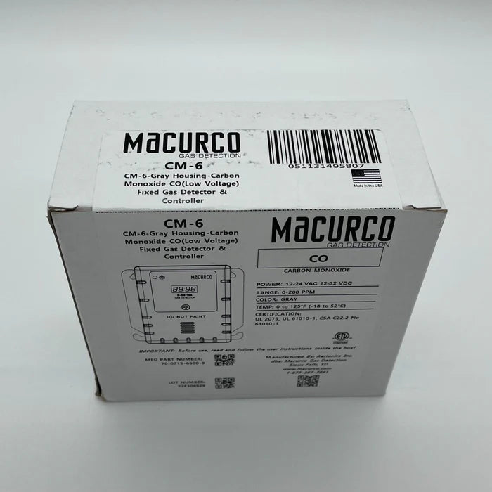 Macurco CM-6 carbon monoxide detector mounted on a wall, with digital display and sensor details visible.