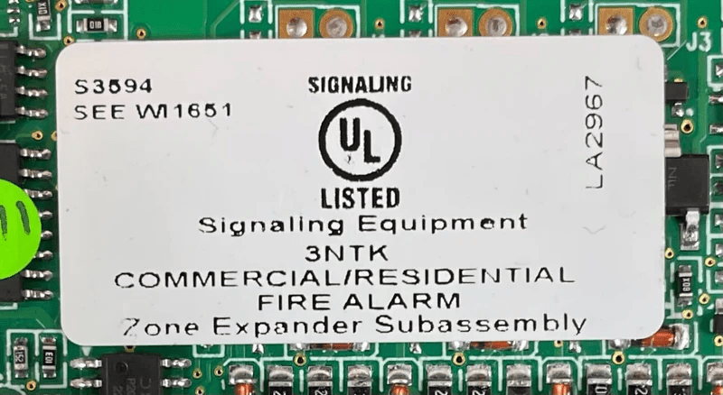 Napco FL-32FACP-LTEVS security alarm control panel mounted on wall with indicator lights and wiring visible.