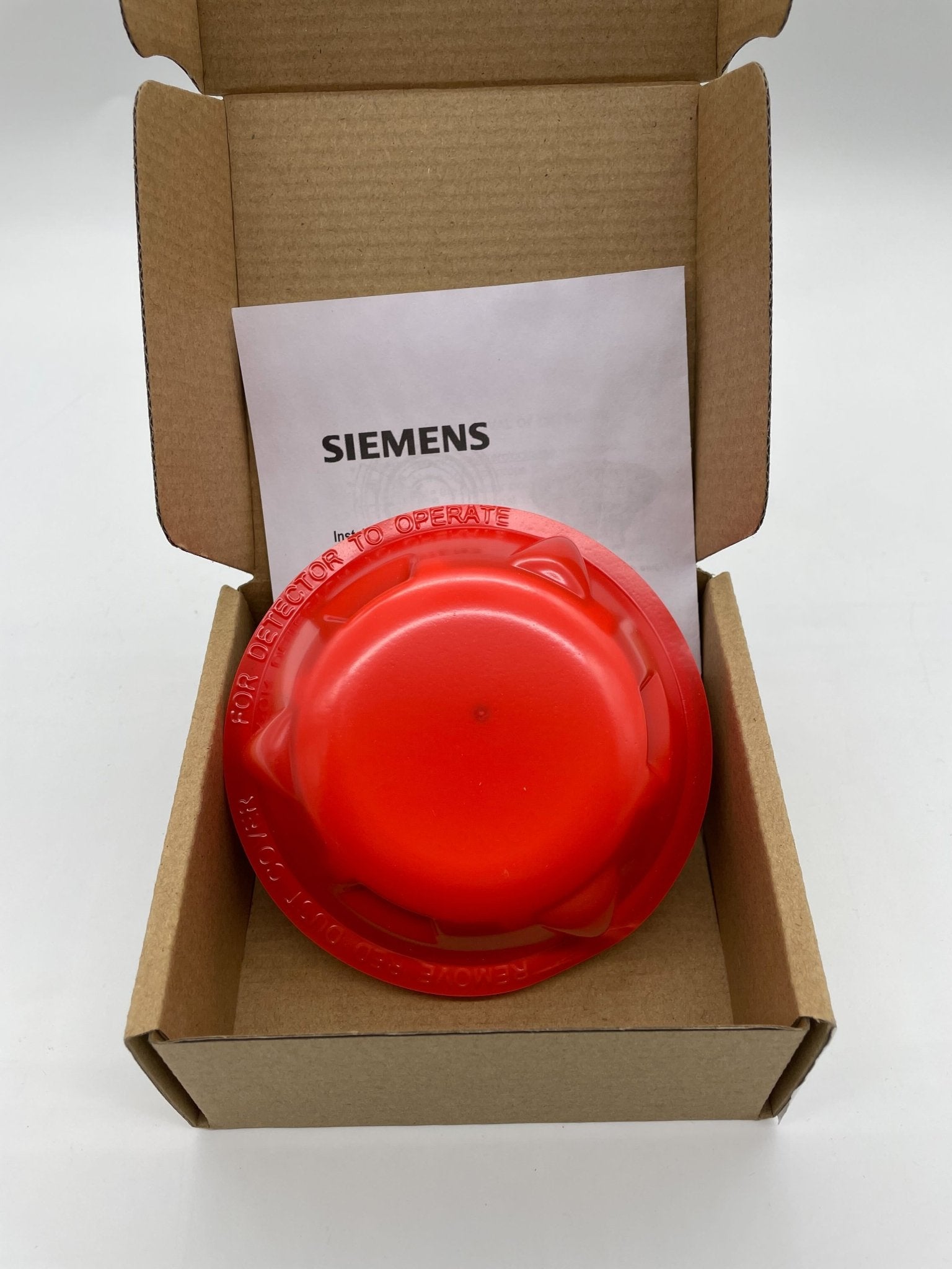 Siemens OP121 smoke detector mounted on ceiling, black round device with sensor openings, designed for fire safety.