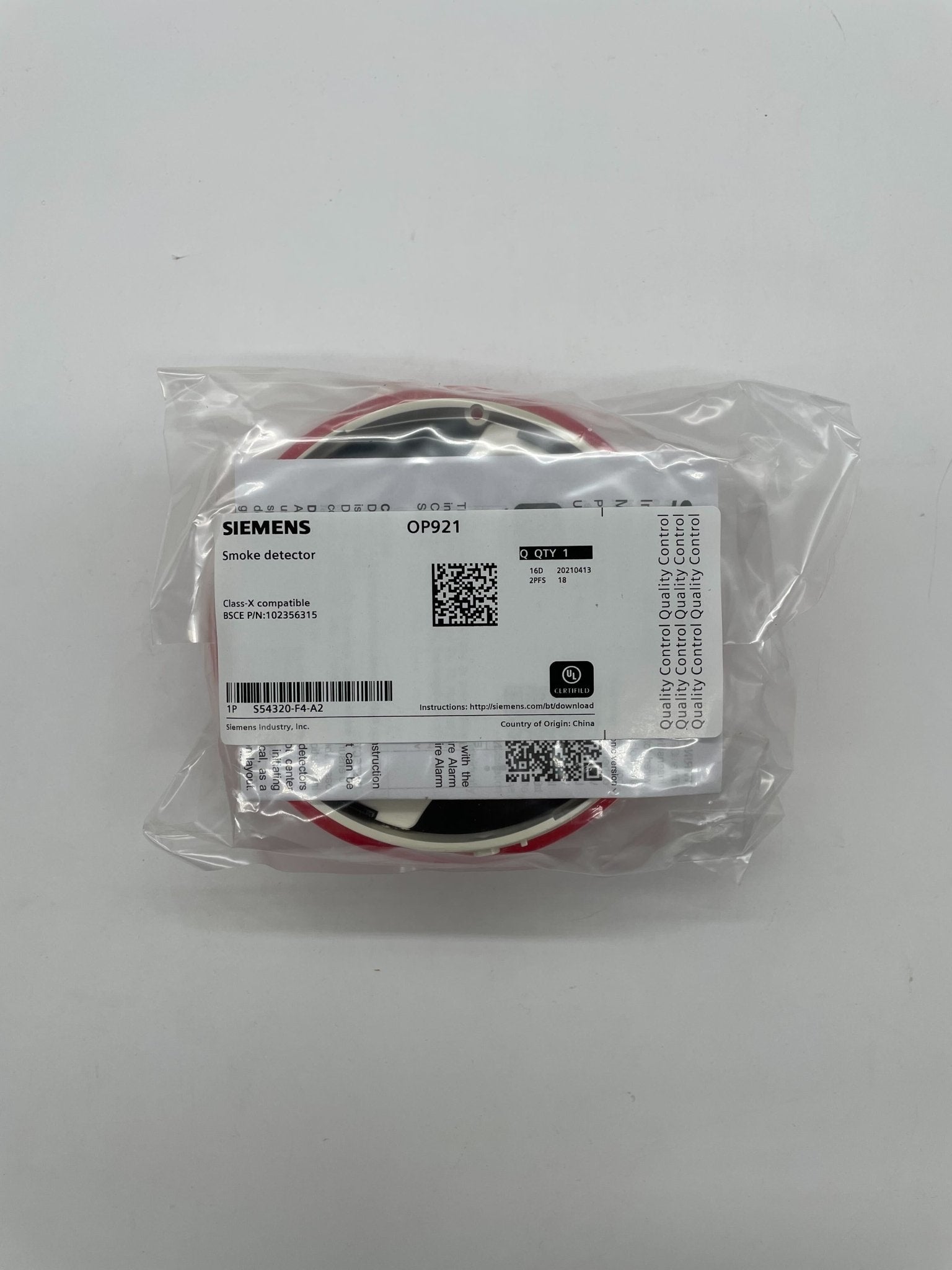 Siemens OP921 smoke detector mounted on ceiling, featuring a sleek white design and sensor for early smoke detection.