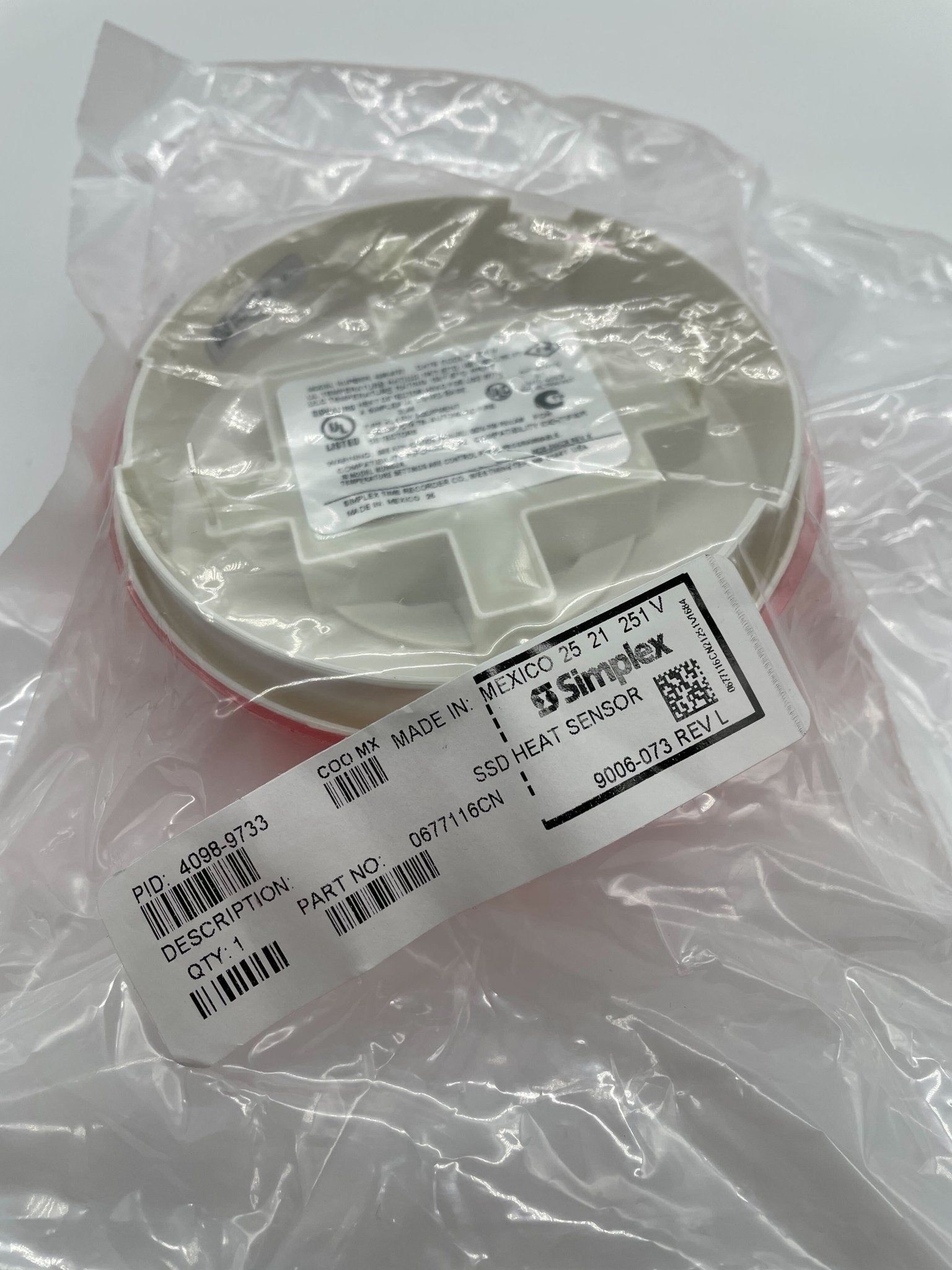 Simplex 4098-9733 heat detector with white casing, mounted on a wall, designed for fire safety and detection systems.
