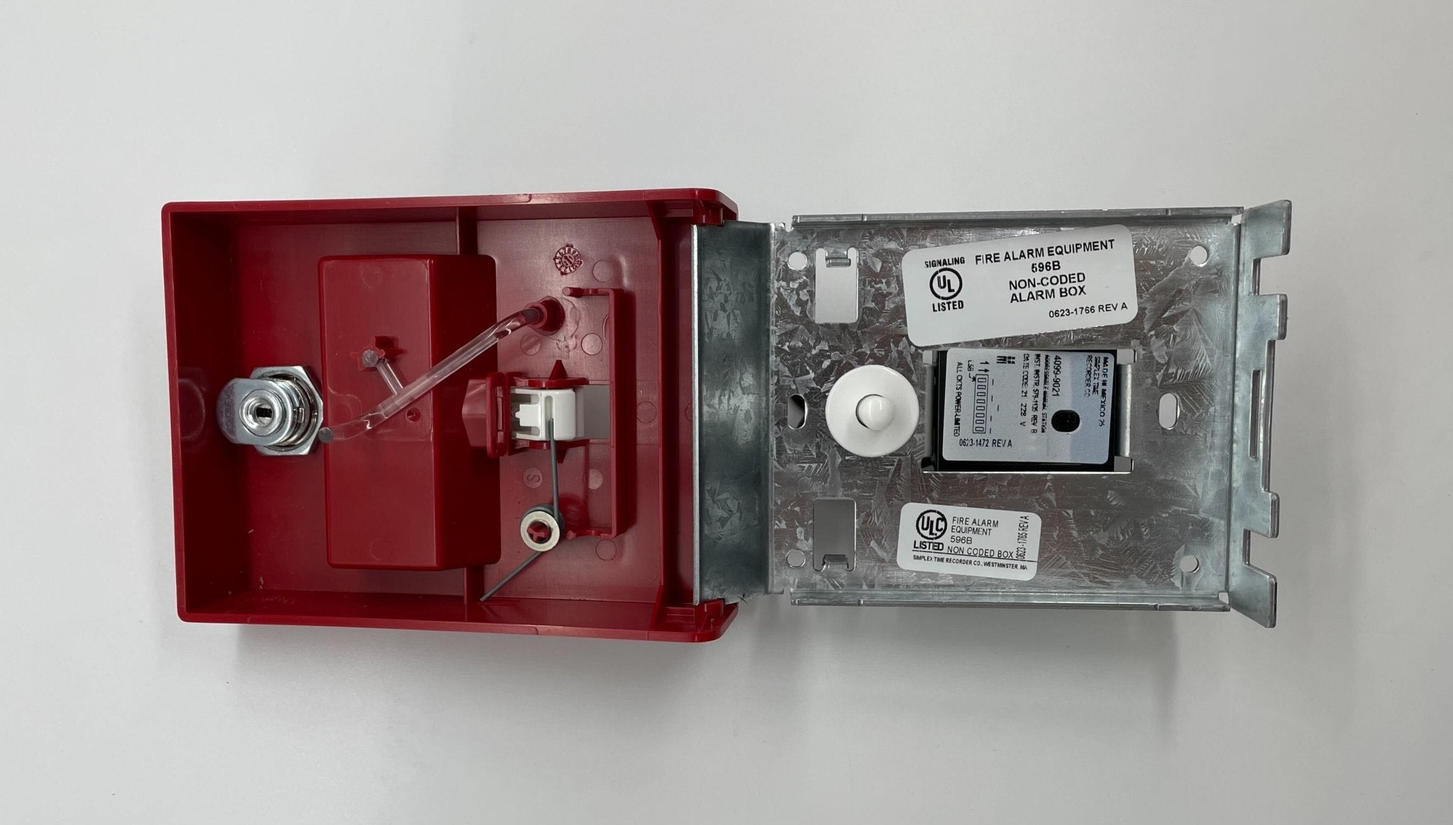 Simplex 4099-9021 pull station fire alarm device mounted on wall, black plastic cover, labeled for emergency use.