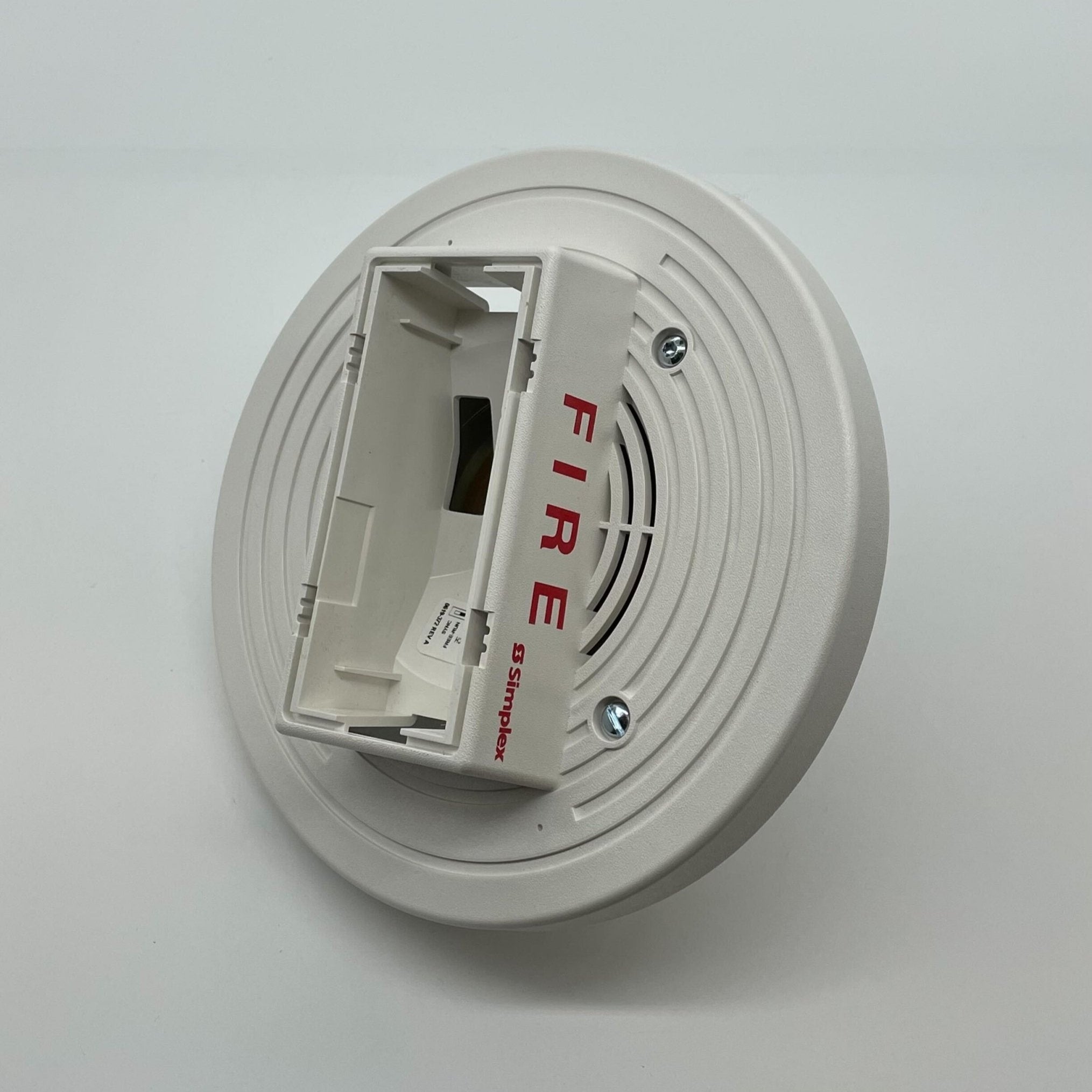 Simplex 4903-9198 fire alarm device, black alarm with test and reset buttons, mounted on a wall.