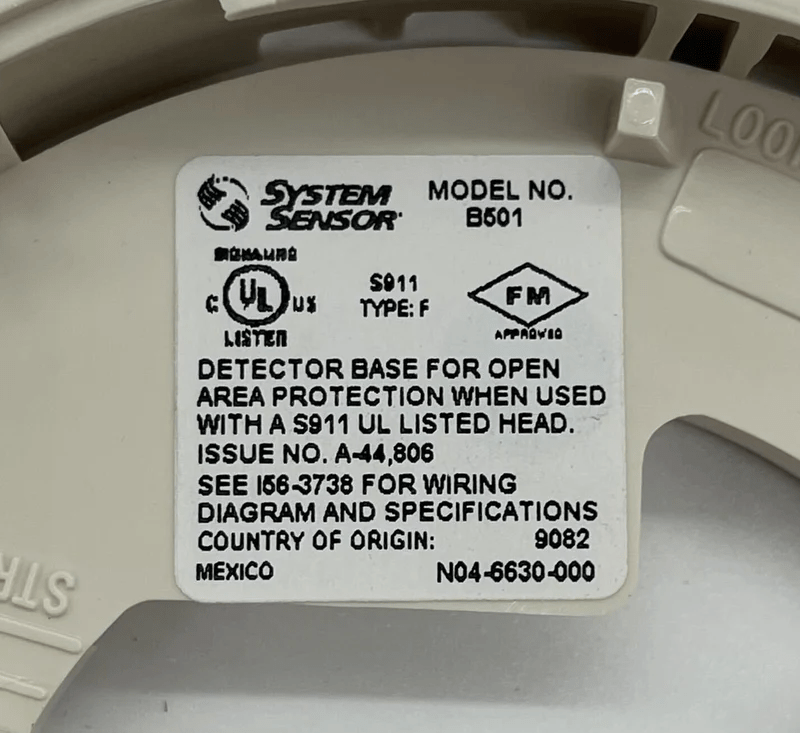 System Sensor B501BP fire alarm detector mounted on ceiling, with wiring and mounting bracket visible.