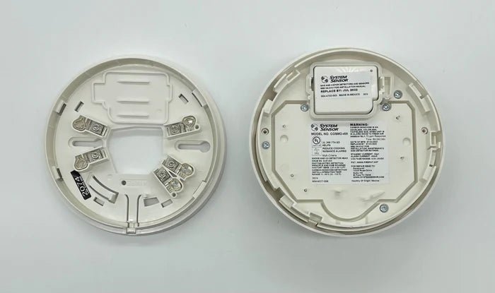System Sensor COSMO-4W smoke detector with wireless connectivity, mounted on ceiling in a modern building.