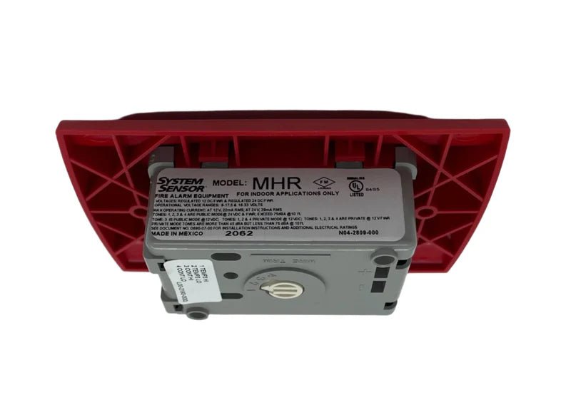 System Sensor MHR fire alarm horn/strobe device mounted on wall, white plastic, with wiring visible for emergency alert signaling.