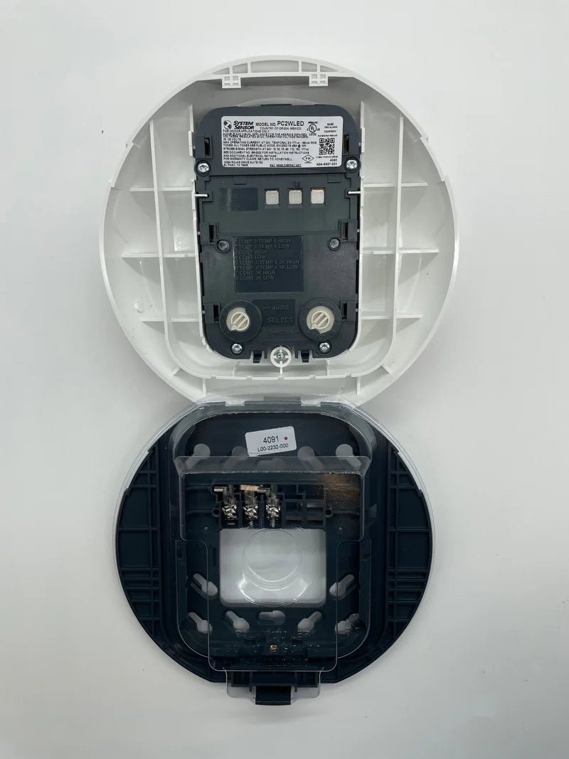 System Sensor PC2WLED LED emergency light with white housing, mounted on a ceiling for safety and illumination.