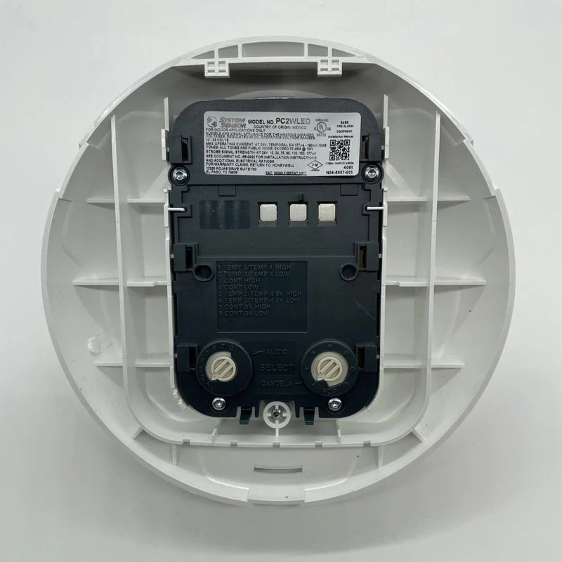 System Sensor PC2WLED LED fire alarm with wiring harness, mounted on wall, showing product details and connection ports.