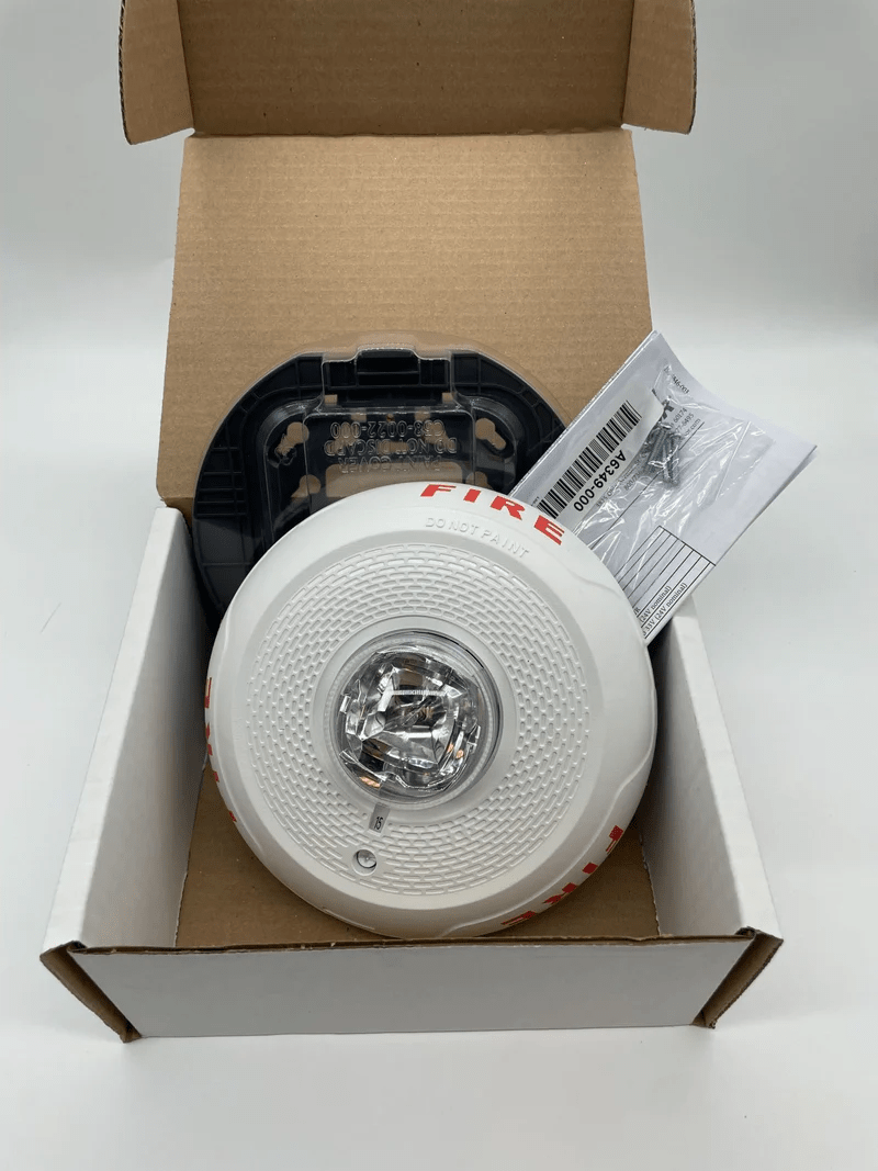 System Sensor SCWL wireless sensor with mounting bracket, used for fire alarm systems, shown in the image.