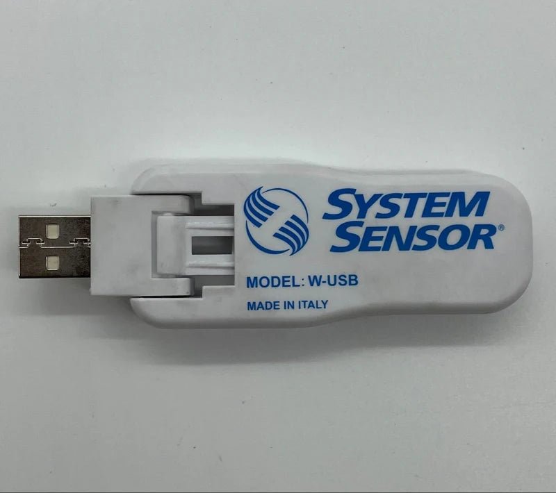 System Sensor W-USB wireless communication module for security systems, shown connected to a control panel.