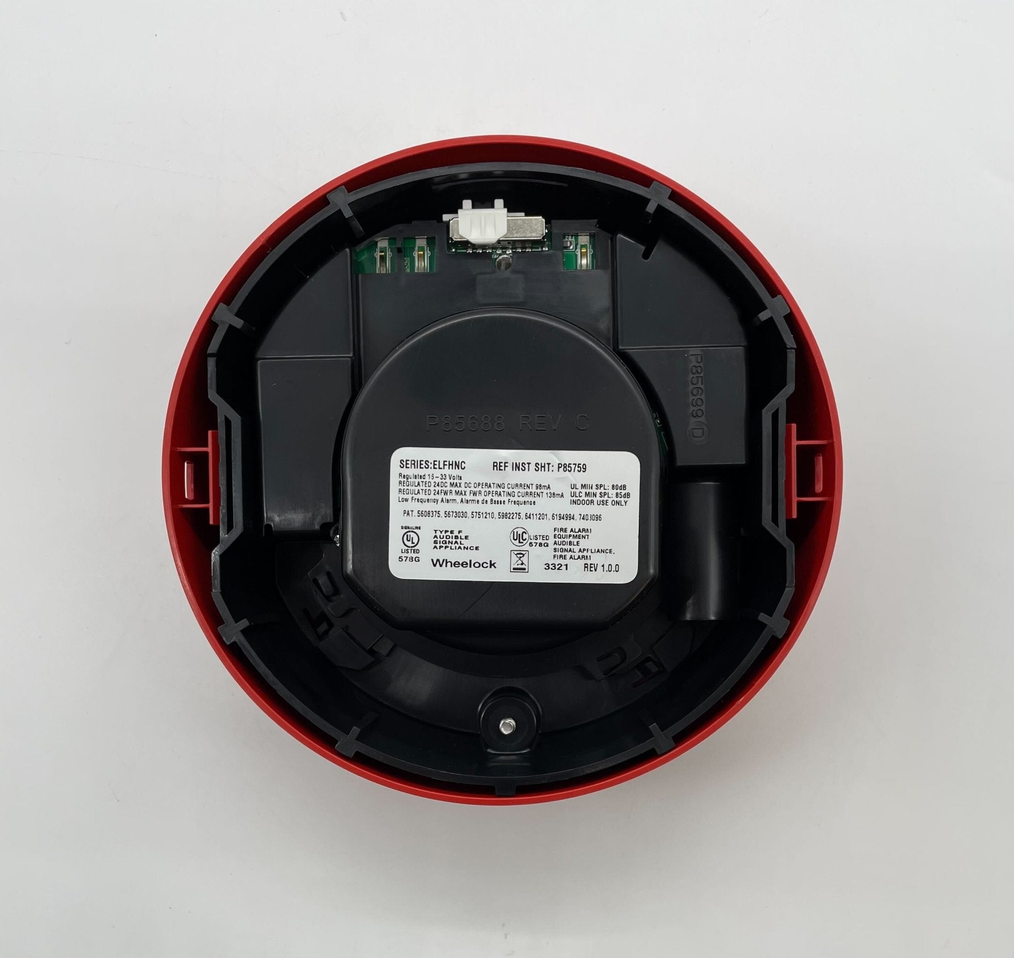 Eaton Wheelock ELFHNRC sounder mounted on a wall, featuring a durable red housing and mounting bracket for industrial signaling.