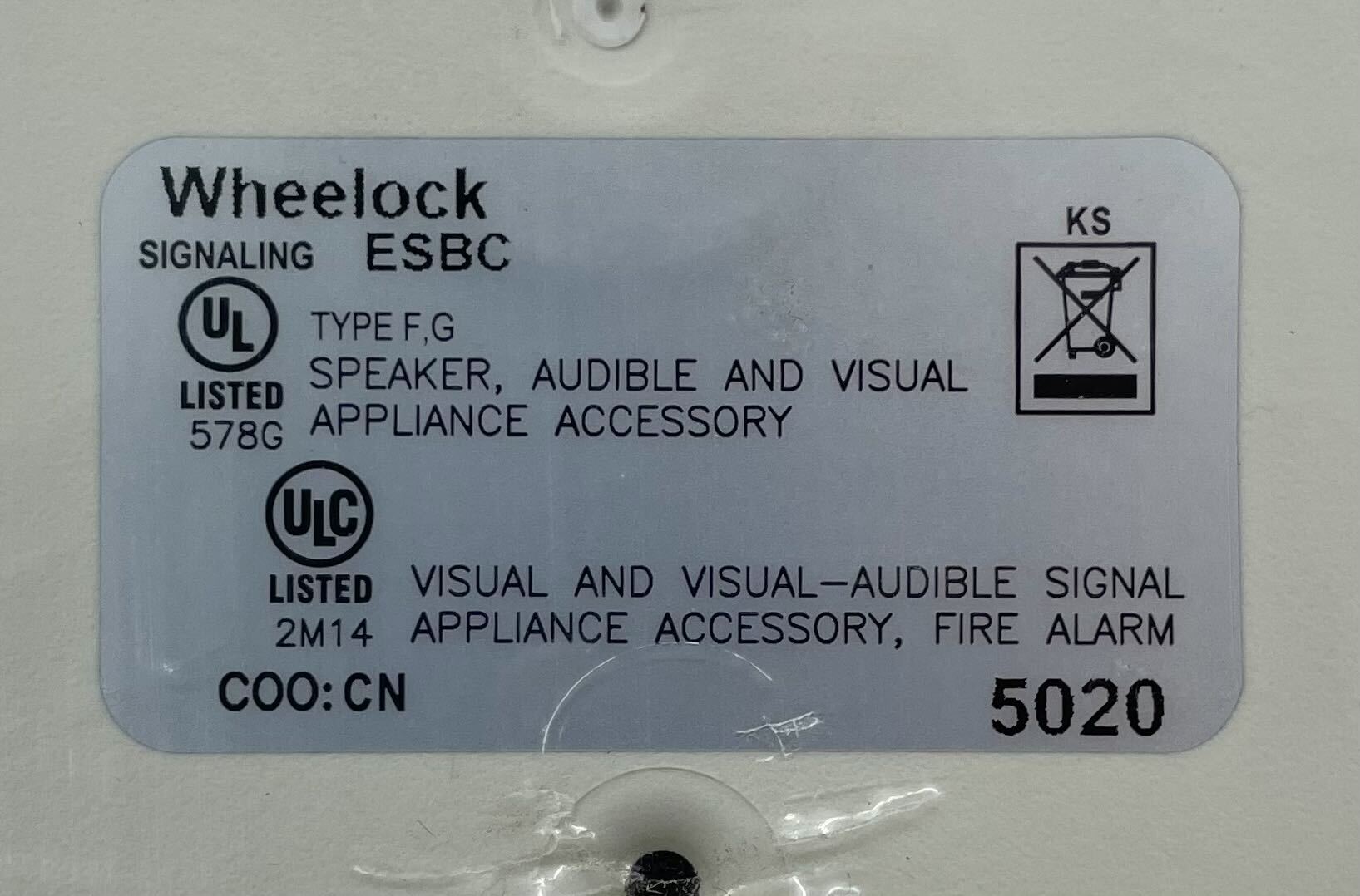 Eaton Wheelock ESBCW fire alarm speaker with mounting bracket, black plastic housing, designed for fire alarm systems.