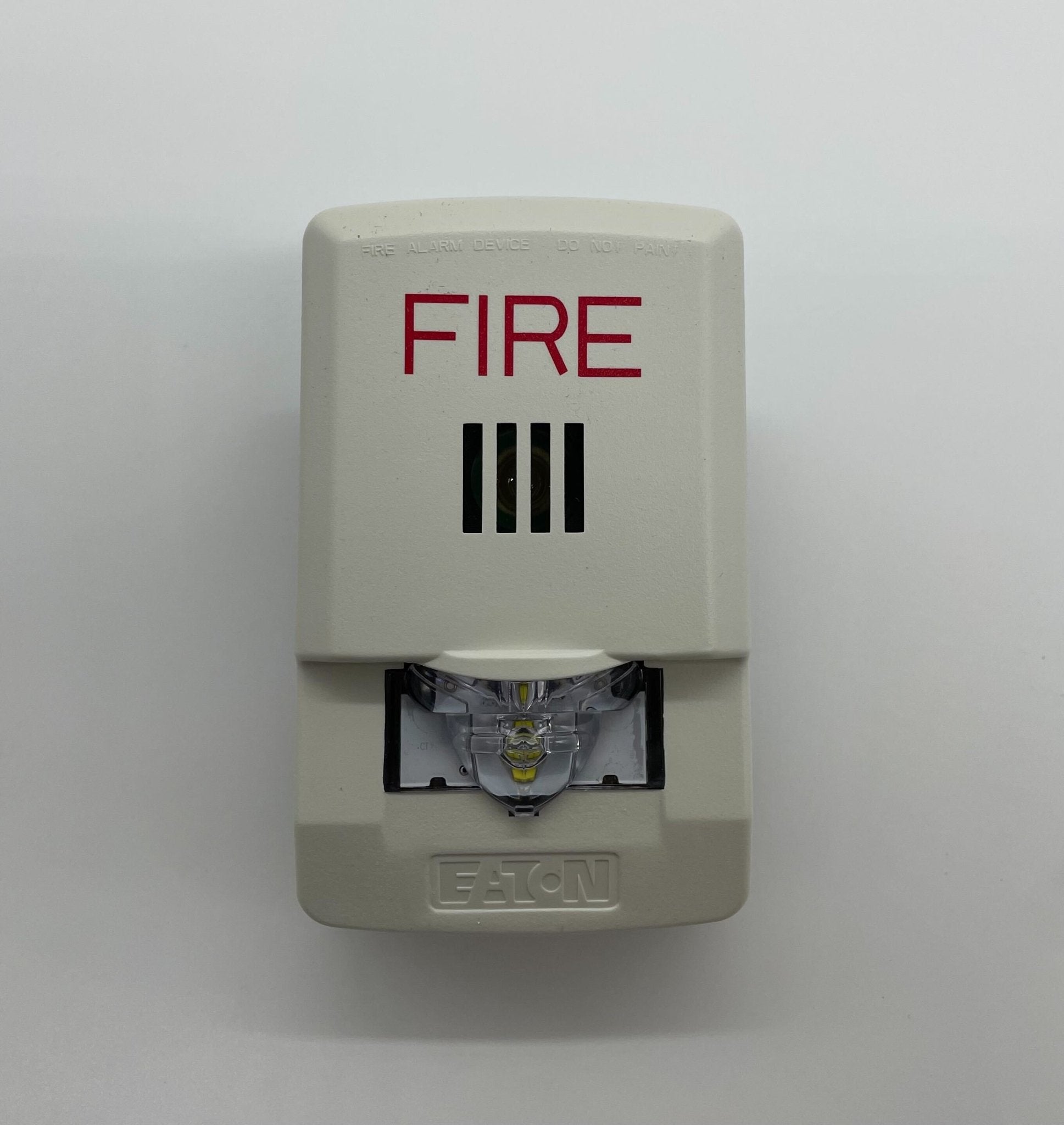 Eaton Wheelock LHSW3 horn strobe alarm in white with flashing light and speaker, mounted on wall for emergency alerting.