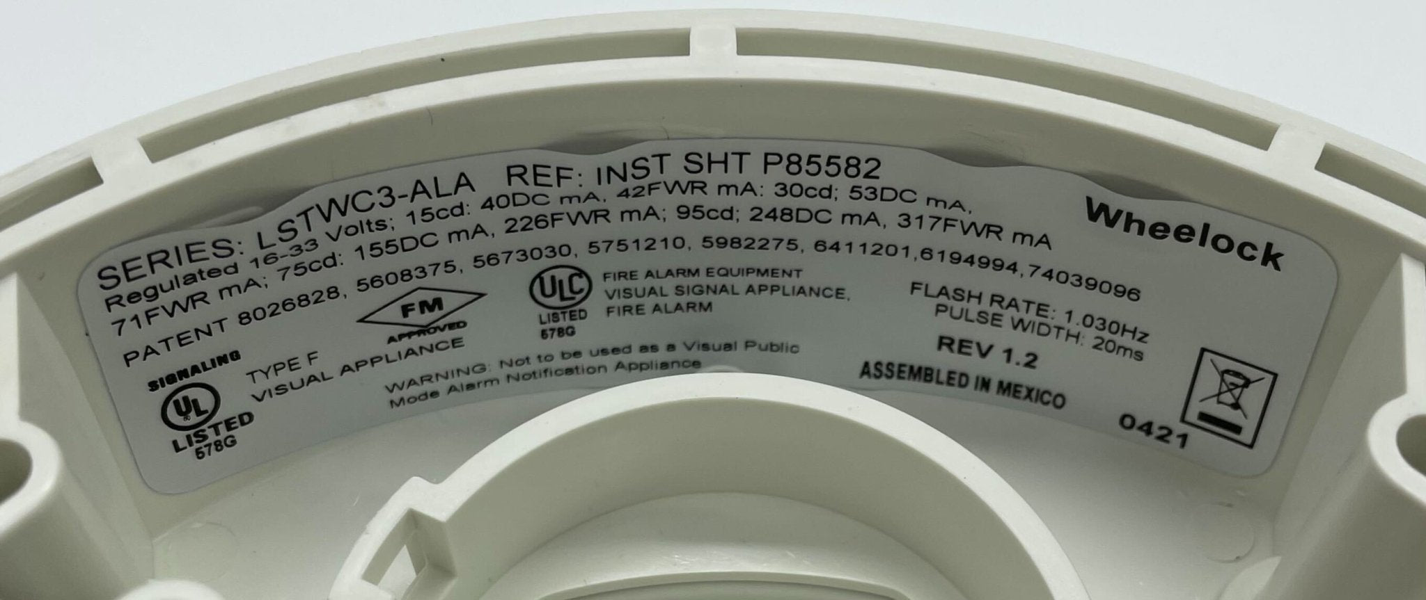 Eaton Wheelock LSTWC3-ALA strobe light in red with clear lens, mounted on a wall, designed for emergency signaling and safety.