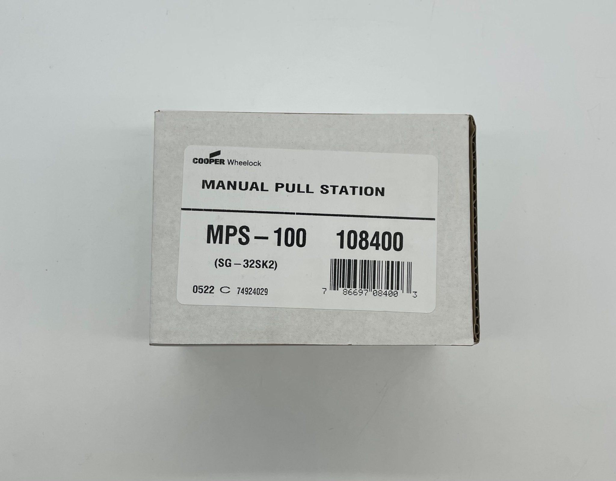 Eaton Wheelock MPS-100 pull station fire alarm device mounted on wall, black plastic cover with red indicator window.