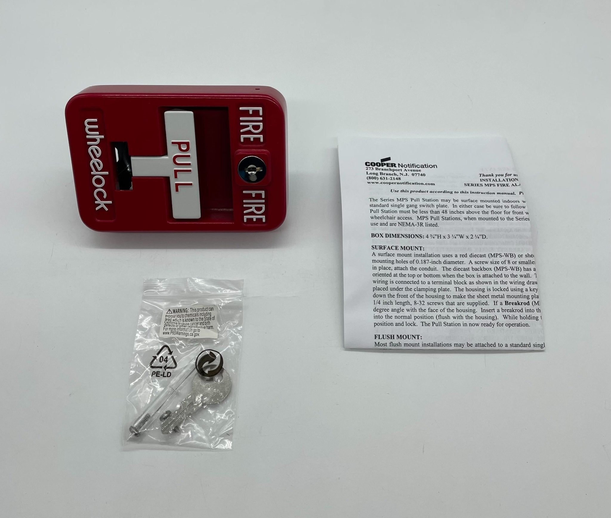 Eaton Wheelock MPS-100 pull station mounted on wall, black metal housing and red pull handle for emergency alarm activation.