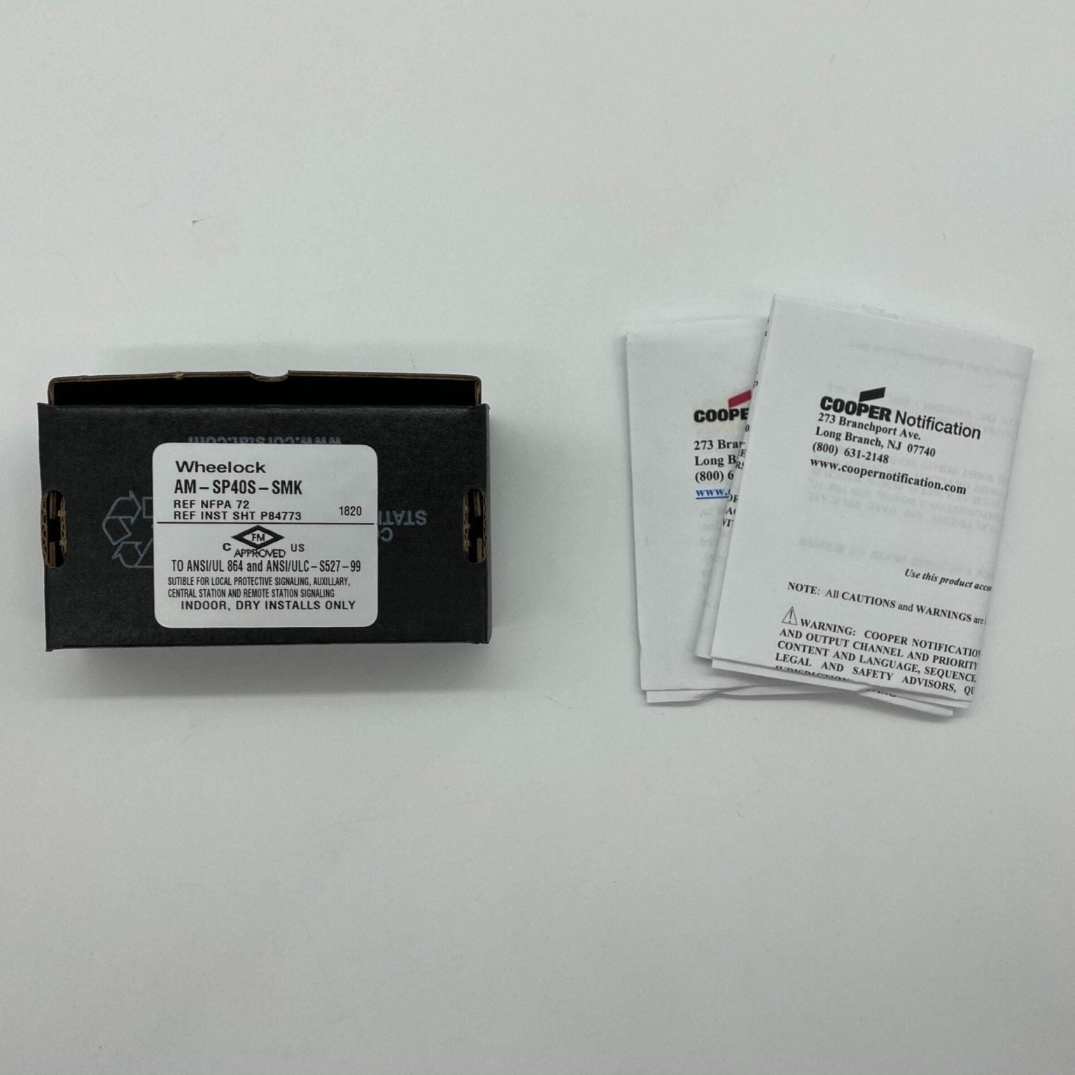 Eaton Wheelock AM-SP40S-SMK fire alarm with smoke detector and alarm horn, mounted on wall in a commercial setting