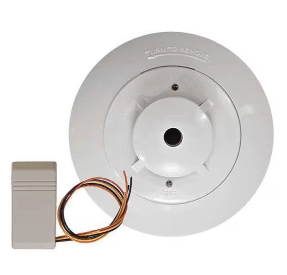 Napco FW-2S fire alarm sensor with ULC certification, mounted on a ceiling, part of the fire safety system in a commercial building.